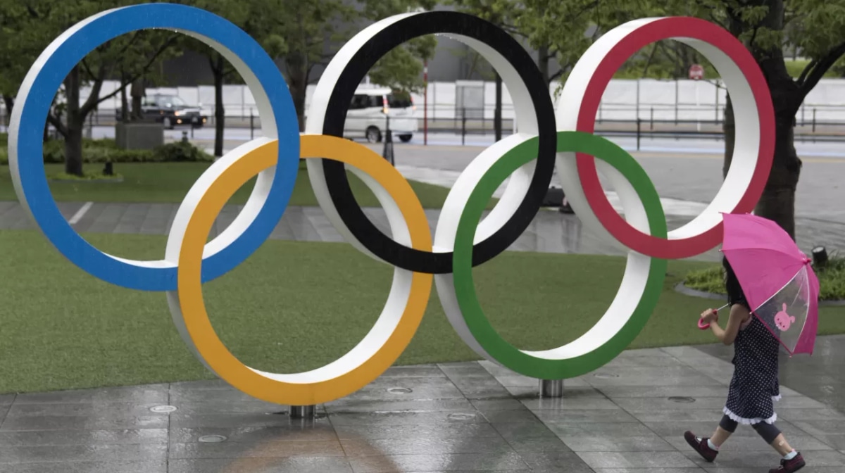  girl walks past the Olympic Rings in front of the National Stadium, the main stadium for the Tokyo Olympic and Paralympic Games, on the day marking one year to go to the Tokyo Olympic Games on July 23, 2020 in Tokyo, Japan. 2020 Summer Olympic Games have